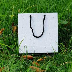 Plantable seed paper bags with black thread lying on grass